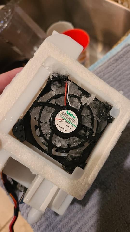 Foam-insulated black fan with red and black wires, mounted inside a white 3D-printed frame.