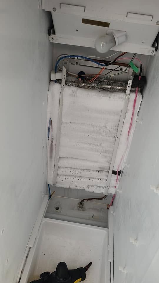 Open service hatch showing insulated ductwork and wiring inside a narrow wall cavity.