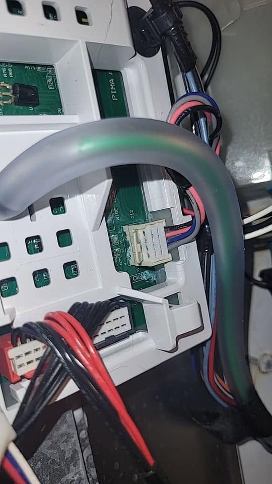 Close-up of tangled cables and connectors inside an electronics panel, with red, black, and gray wires.