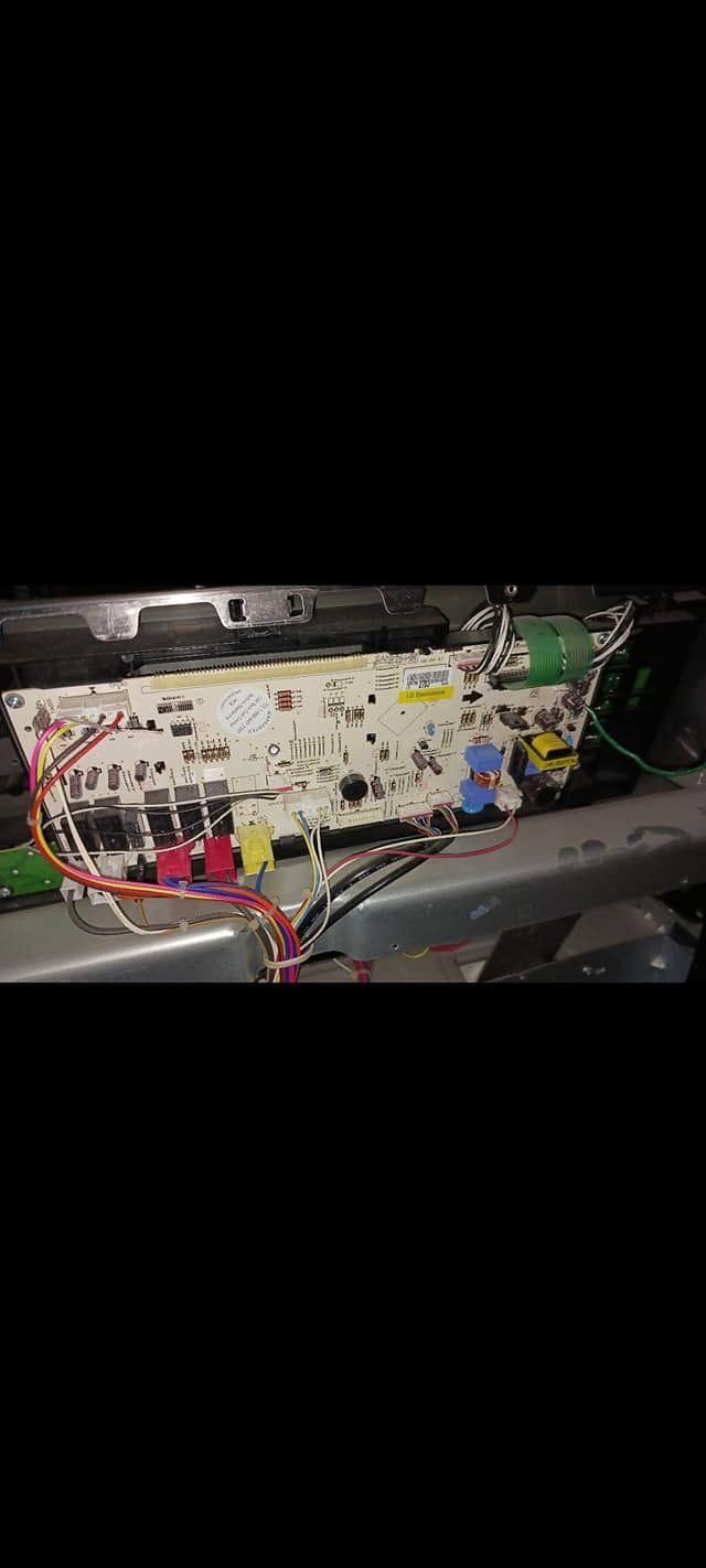 Open electronic control panel with wires, circuit boards, and colored connectors inside a machine cabinet