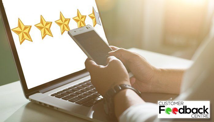 Hands holding a smartphone over a laptop with five gold stars and 