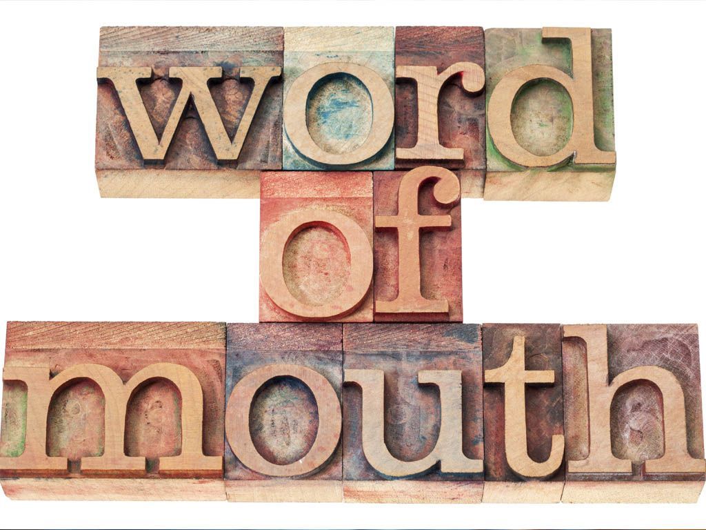 Wooden letter blocks spelling “word of mouth” on a white background