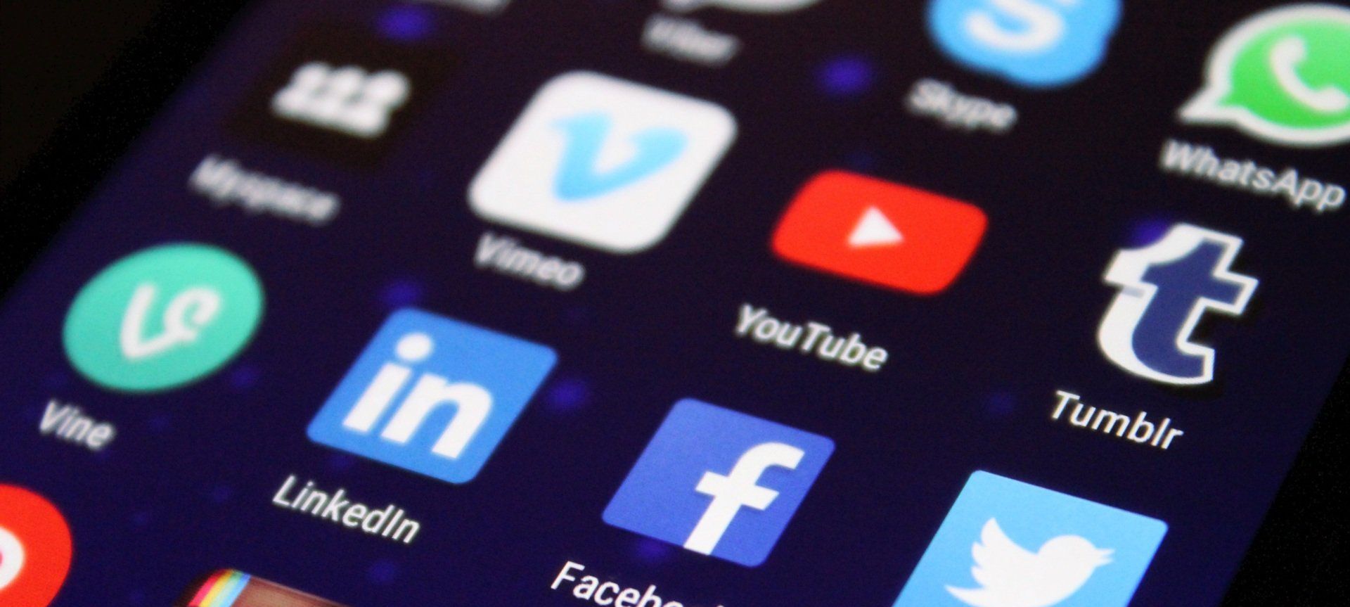 Close-up of smartphone screen with social media app icons, including YouTube, LinkedIn, Facebook, and Twitter.