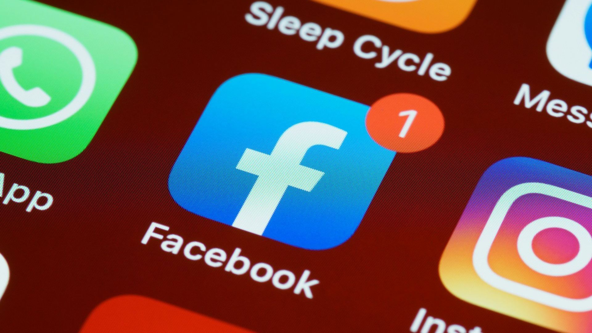 Close-up of smartphone app icons including Facebook with a red notification badge and Instagram on a red background