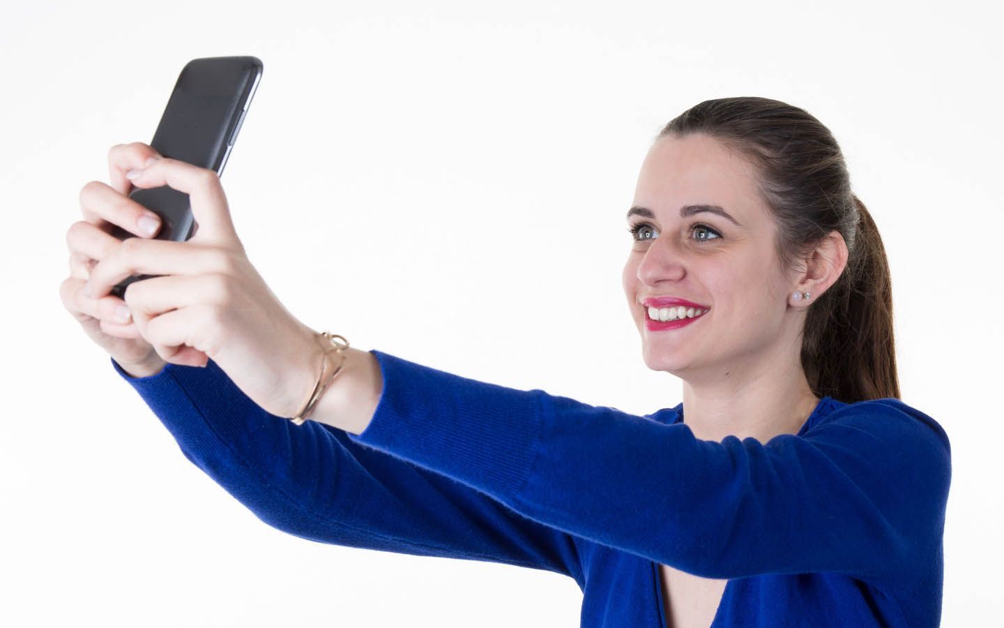 Smiling woman in a blue sweater taking a selfie with a smartphone