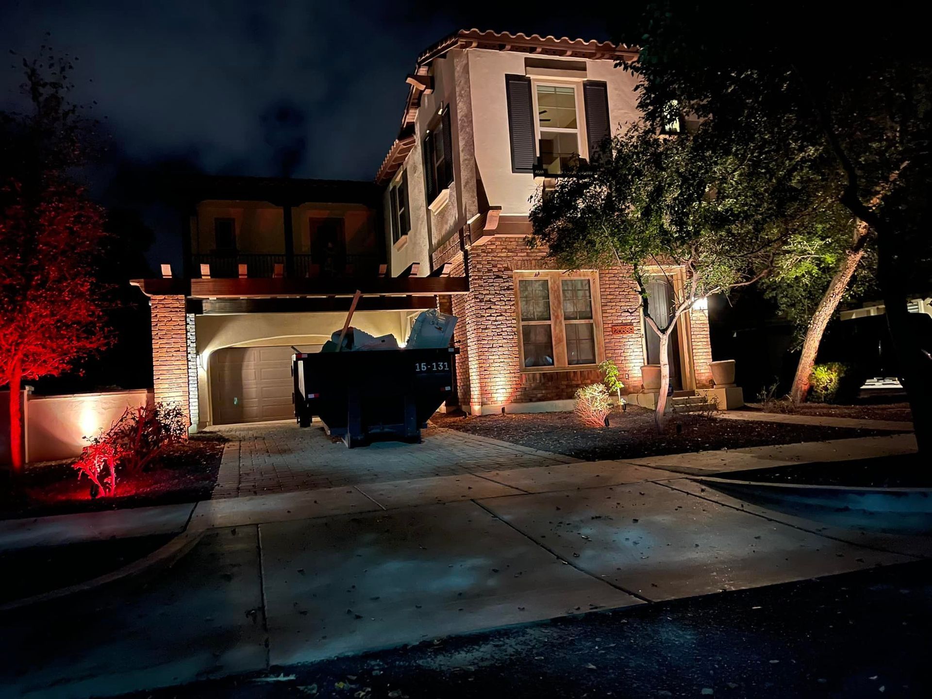 Nighttime view of a two-story house with a driveway, garage, parked truck, and lit front entrance