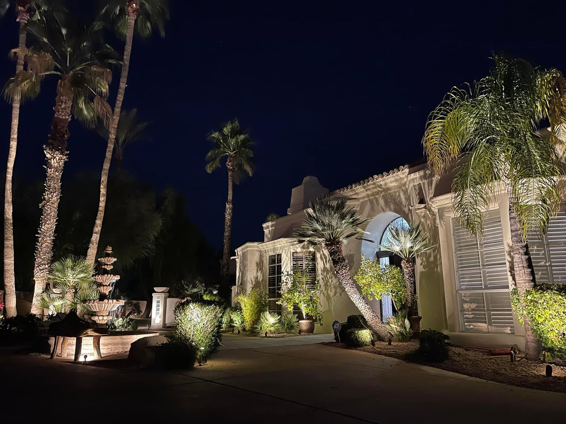 Lit stone building and palm trees at night with warm landscape lighting