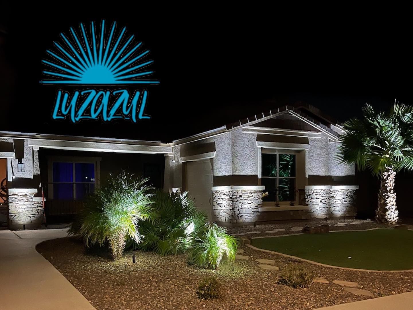 Nighttime photo of a house with bright exterior lights, a lit front yard, and a turquoise logo overlay in the sky.