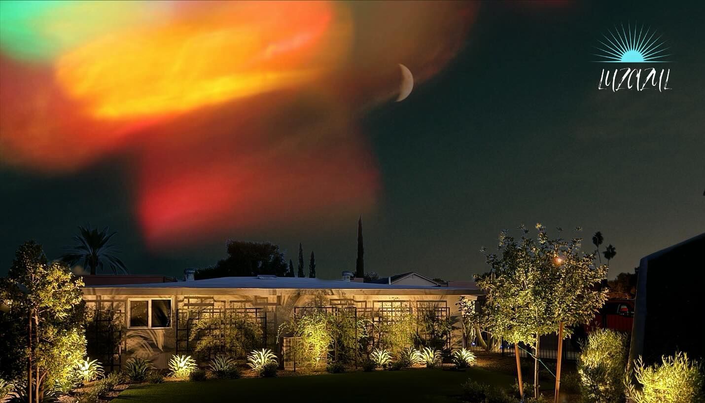 Night sky over a lit building with glowing orange clouds and trees in the foreground