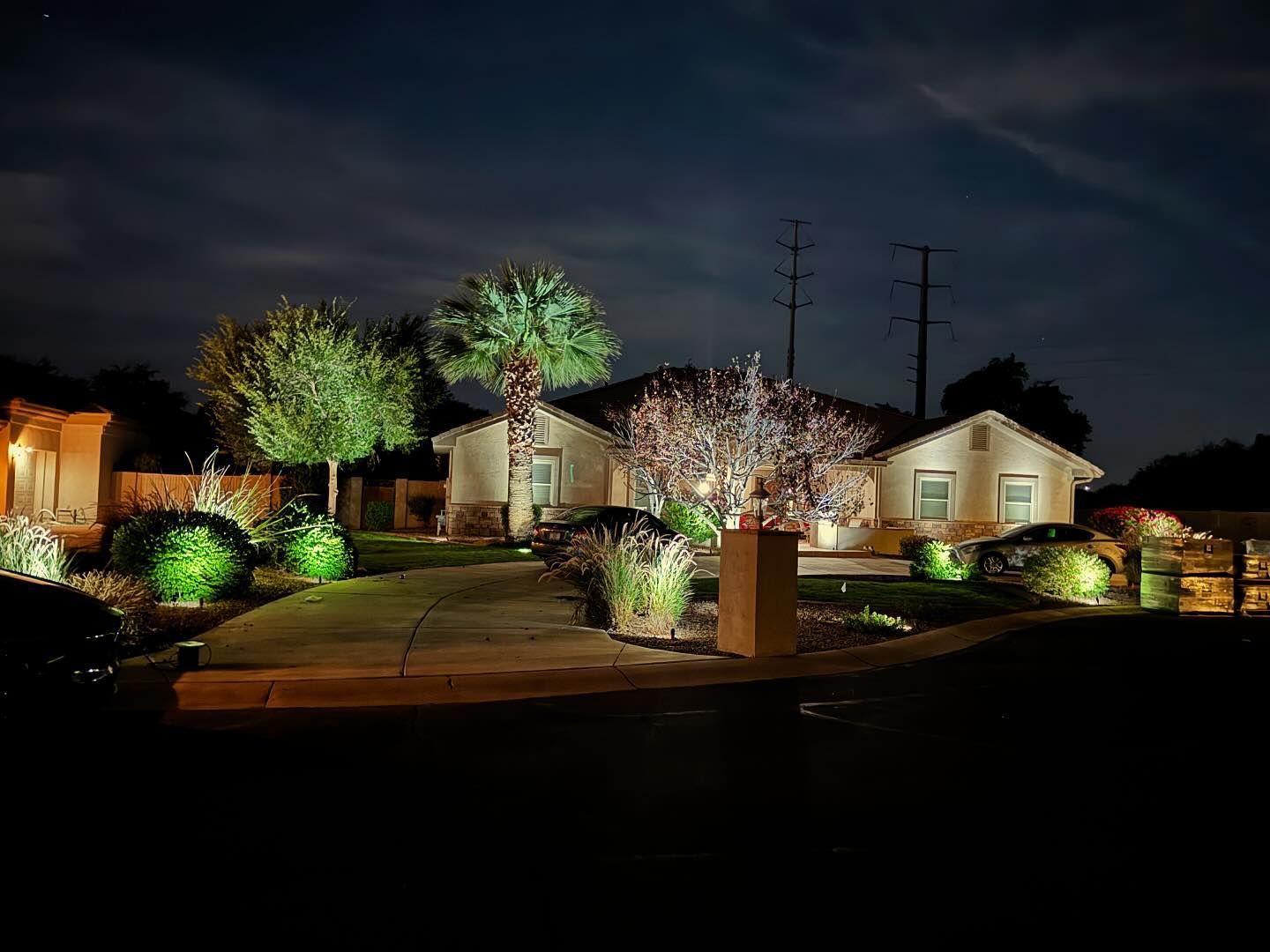 Suburban homes and landscaped front yards lit up at night under a dark sky