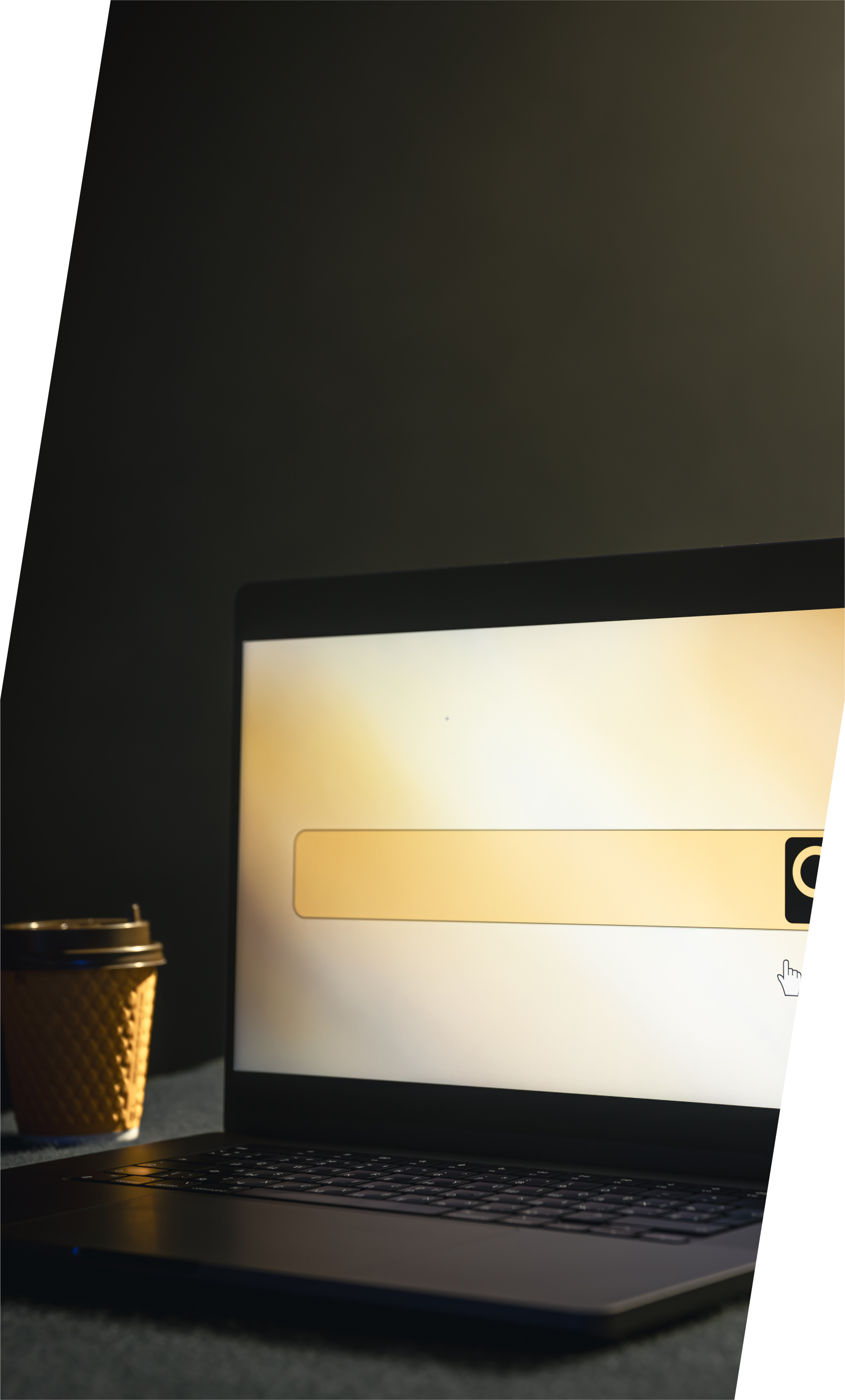 Laptop with search bar, coffee cup, dark background, warm lighting.