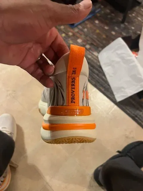 A person is holding a pair of shoes with the word proverbs on it