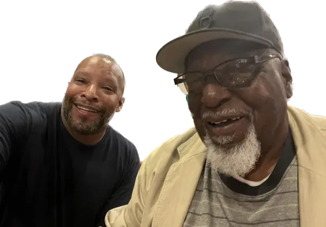 Two men are posing for a picture and one has a hat on