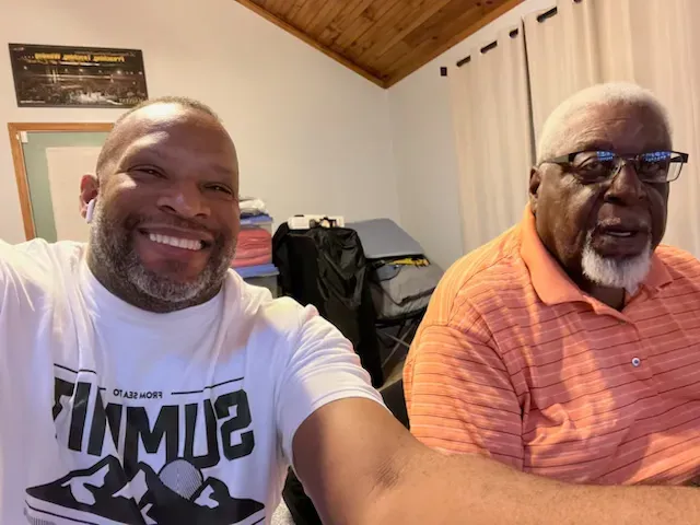 Two men are posing for a picture with one wearing a shirt that says summit