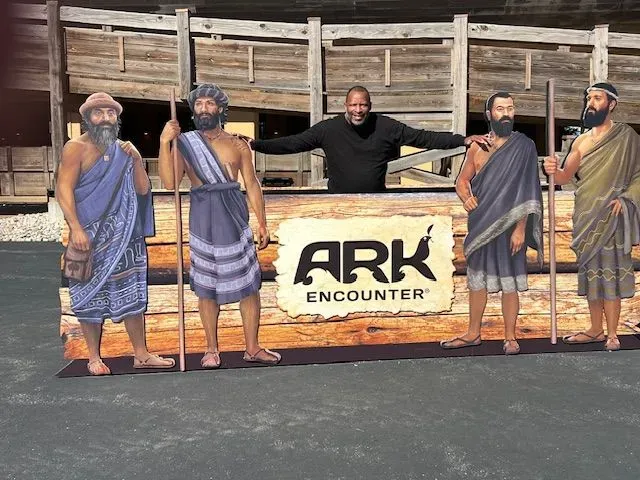 A man is standing in front of a sign that says ark encounter