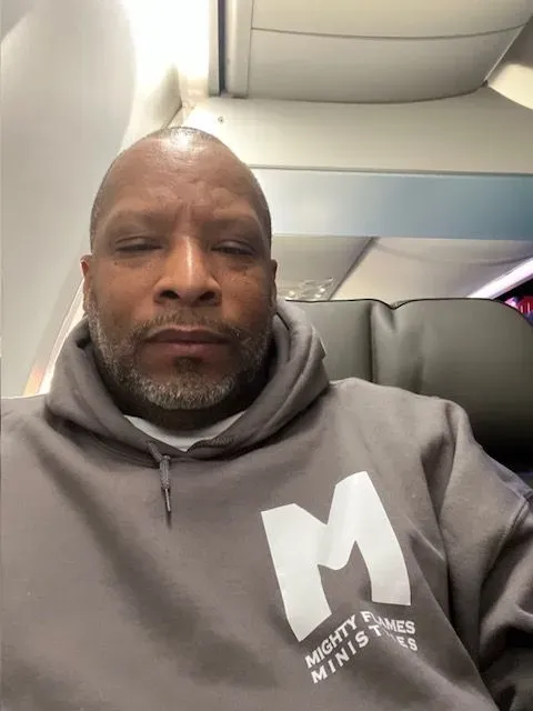 A man wearing a grey hoodie with the letter m on it