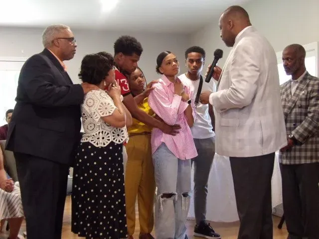 A group of people standing around a man holding a microphone