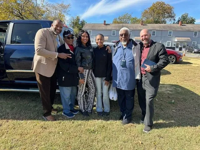 A group of people are posing for a picture in front of a van.
