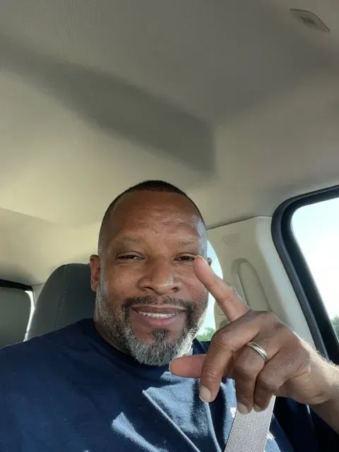 A man is sitting in the driver 's seat of a car giving a peace sign.