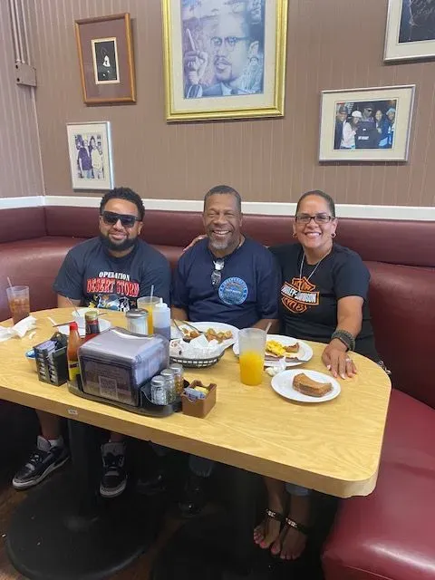 Three people are sitting at a table with plates of food.