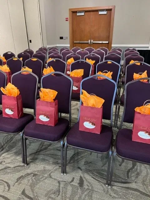 Rows of purple chairs with red bags on them