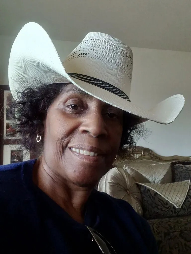 A woman wearing a cowboy hat is smiling for the camera.