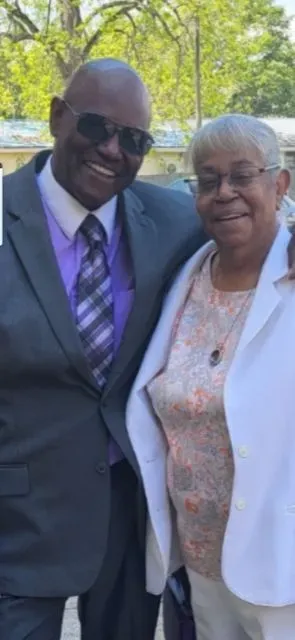 A man in a suit and tie is standing next to a woman in a white jacket.