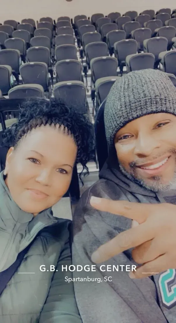 A man and a woman are posing for a picture in front of a row of chairs.