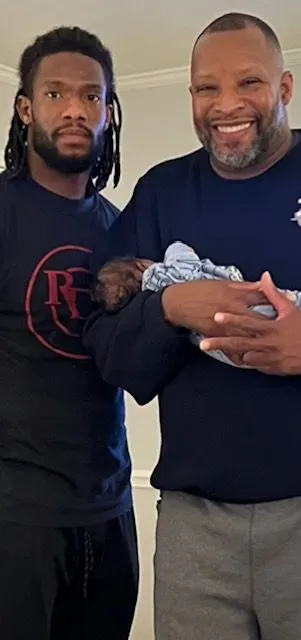 Two men are standing next to each other holding a baby.
