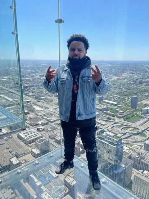 A man is standing on top of a glass platform overlooking a city.