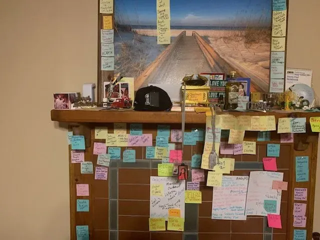 A fireplace with sticky notes on it and a picture on the wall