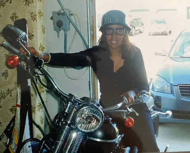 A woman leaning on a motorcycle in a garage