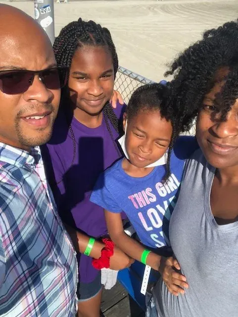 A family posing for a picture with a girl wearing a shirt that says this girl loves us