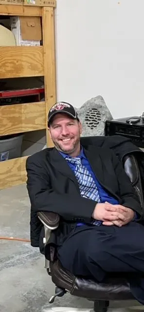 A man in a suit and tie is sitting in an office chair.