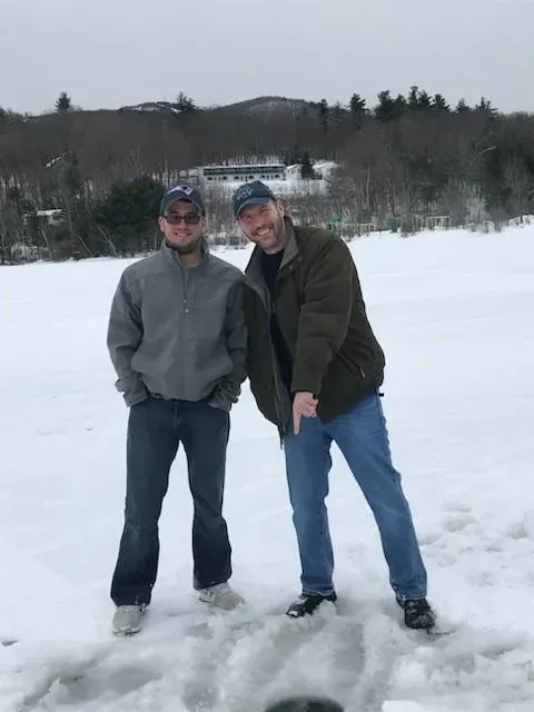 Two men are posing for a picture in the snow