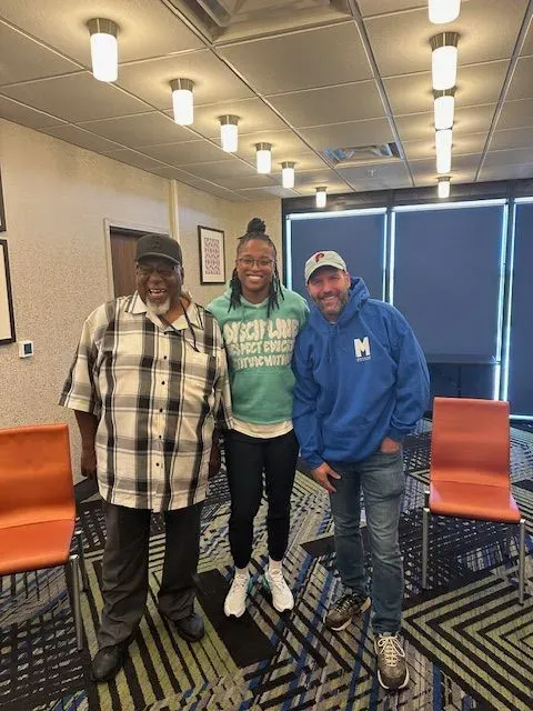 Three people are posing for a picture in a room.
