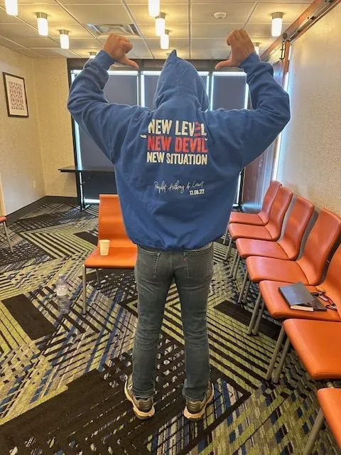 A person wearing a blue hoodie that says new level new devil new situation