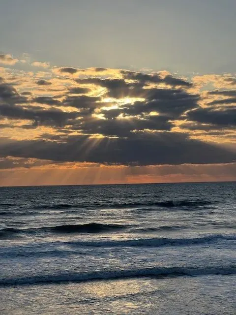 The sun is shining through the clouds over the ocean