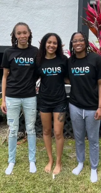 Three people wearing vous t-shirts are posing for a picture