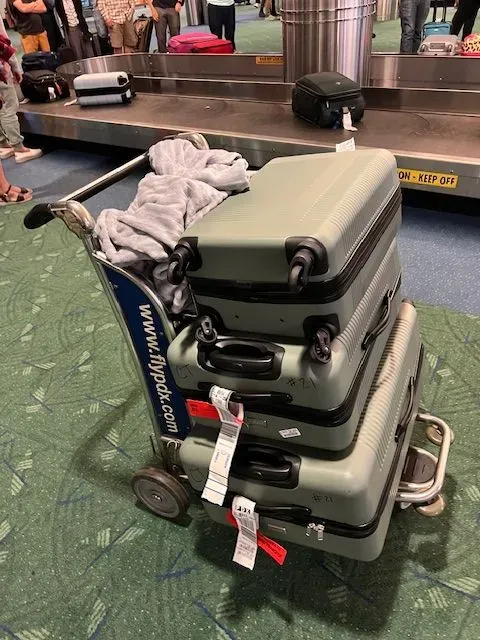 Three suitcases are stacked on top of each other on a cart.