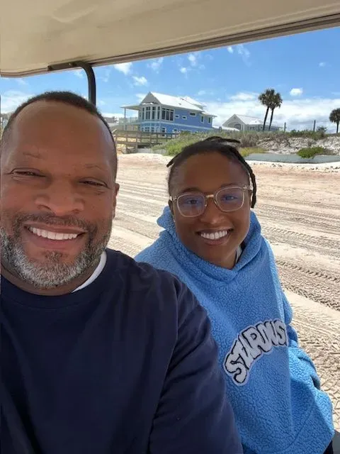 A man and a woman are sitting in a golf cart.