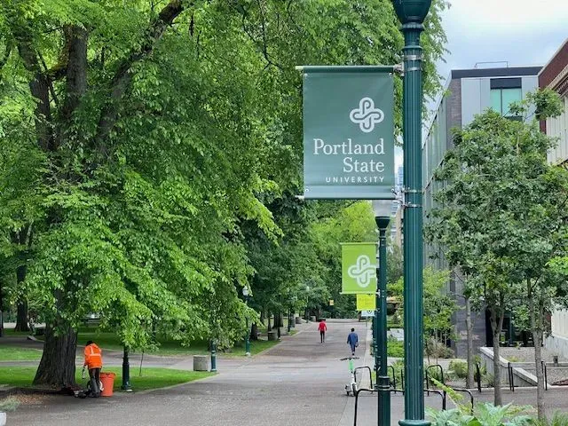 A sign for portland state university hangs from a street light