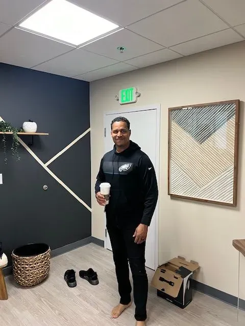 A man is standing in a room holding a cup of coffee.