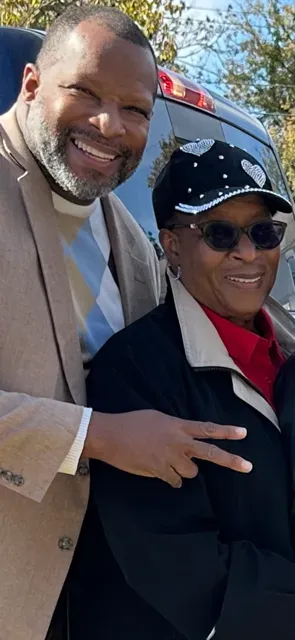 A man and a woman are posing for a picture in front of a car.