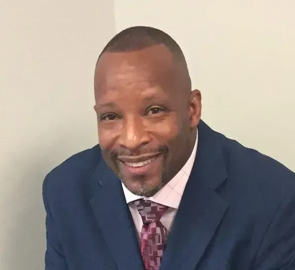 A man in a suit and tie is smiling for the camera.
