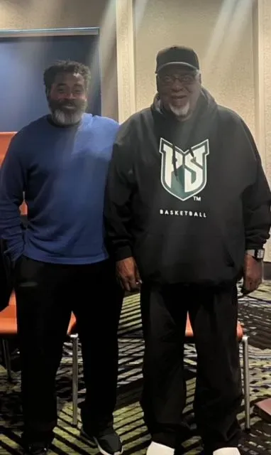 Two men standing next to each other one wearing a ps sweatshirt