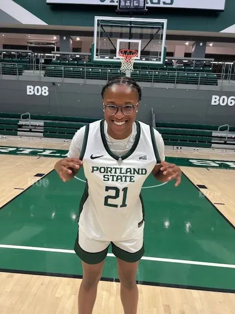 A woman wearing a portland state jersey is standing on a basketball court.