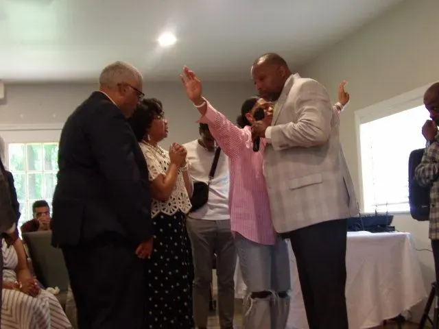 A group of people are standing in a room with their hands in the air