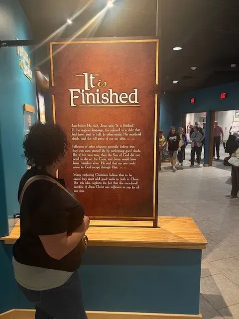 A woman is standing in front of a sign that says it is finished.