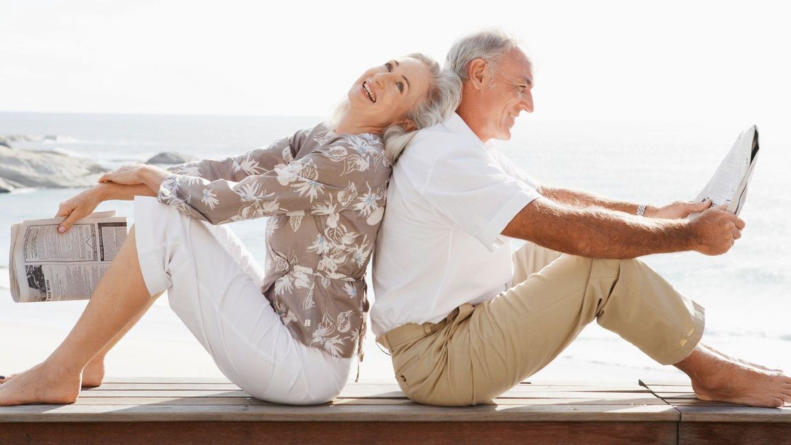 a man and a woman are sitting back to back on a pier 